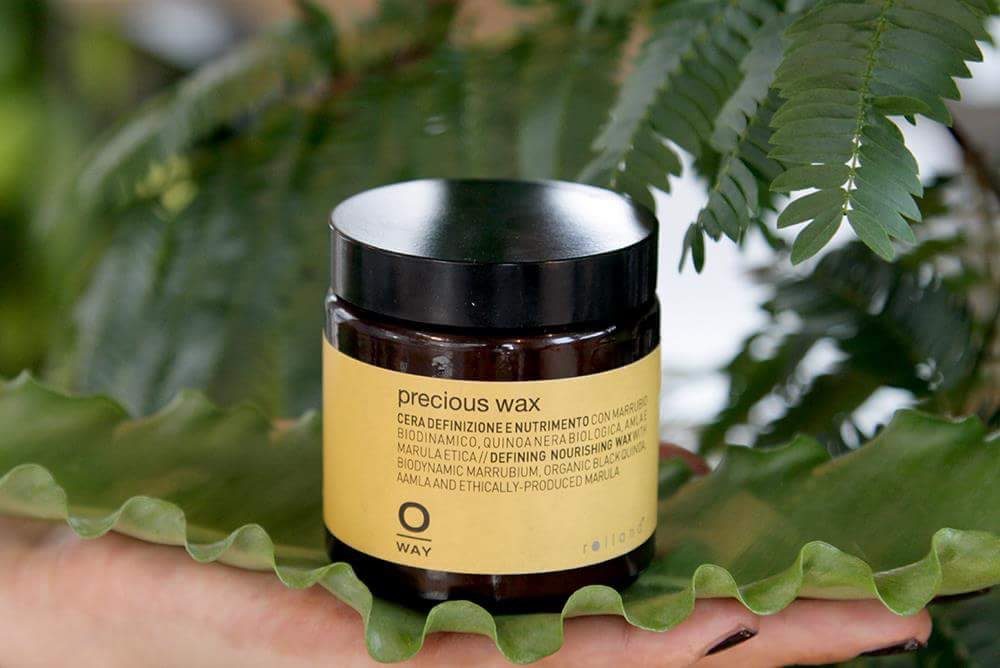 Pot de precious wax OWAY posé sur une grande feuille verte.